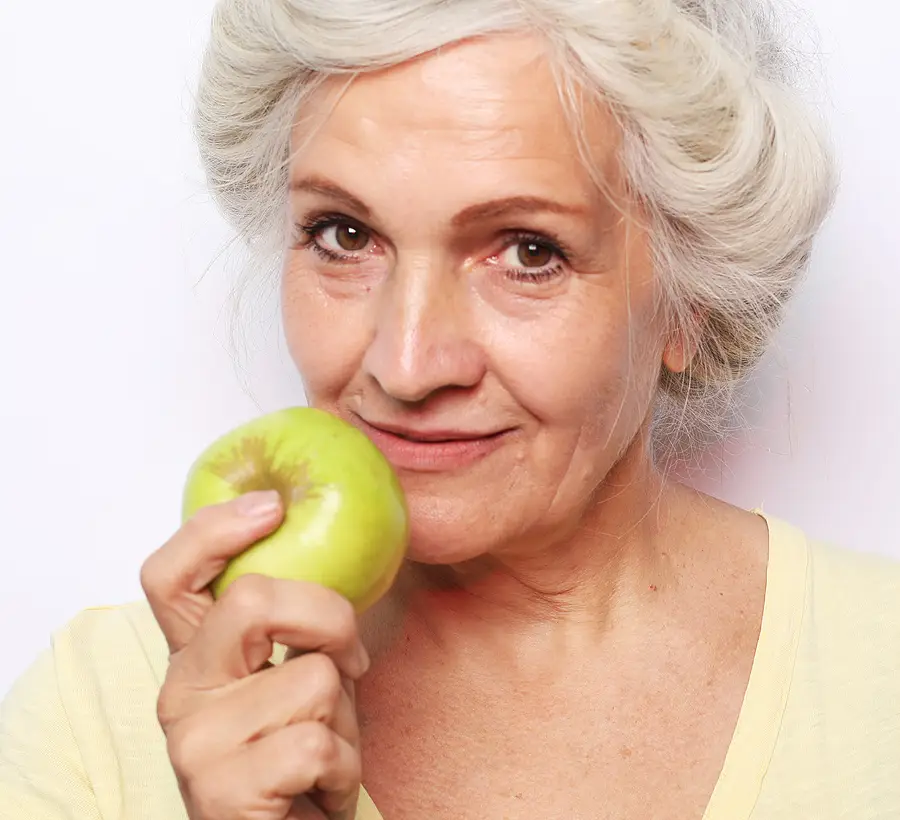 Portrait of a beautiful elderly woman holding an apple, smiling,